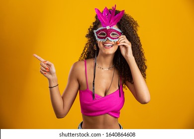 Beautiful woman dressed for carnival night. Smiling woman ready to enjoy the carnival with a colorful mask. Pointing side.