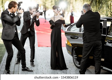 Beautiful woman dressed in retro style as a famous movie actress arriving on the awards ceremony with photo reporters taking pictures of her