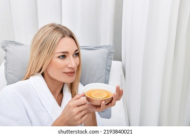 Beautiful woman drinking relaxing herbal tea with lemon at spa center after relax relaxing treatments and massage - Powered by Shutterstock