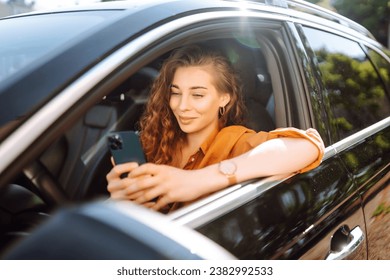 Beautiful woman driver in a car with a phone in her hands. The driver of the car uses a smartphone. Leisure, travel, technology, navigation. - Powered by Shutterstock