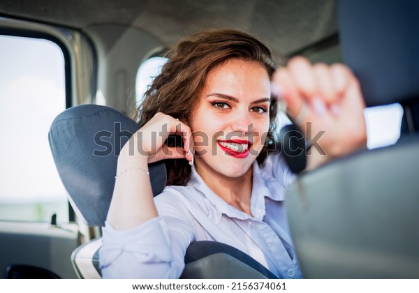 Beautiful woman driver showing car key and smiling\
while sitting inside her new car.Rental or buying auto concept.Auto\
insurance concept\
image.