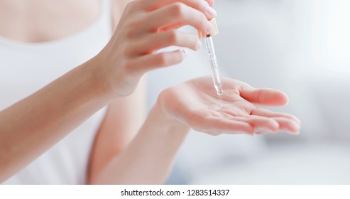 beautiful woman dropping collagen moisturizer into her hand at home - Shutterstock ID 1283514337