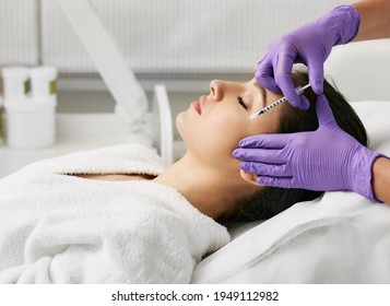 Beautiful woman during facial mesotherapy. Beautician doing anti-aging injection for tightening skin and remove eye wrinkles