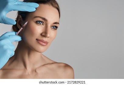 Beautiful woman during facial mesotherapy for smoothing of mimic wrinkles around eyes with beautician. Anti-aging injections for rejuvenation and lift skin