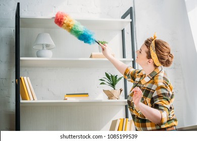 Beautiful Woman Dusting Shelves At Home