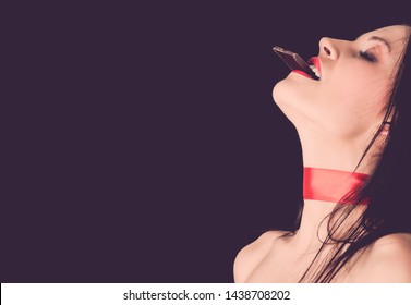 Beautiful woman eating dark chocolate with close eyes. Enjoyment concept.