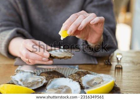 Beautiful Woman eating fresh oysters and drinking in restaurant. Seafood delicacies. oysters with lemon