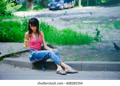 beautiful woman eating ice cream sitting on the sidewalk in the city, summer heat.