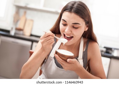 beautiful woman eating yogurt at the kitchen