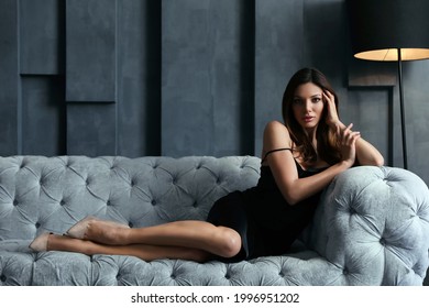 Beautiful Woman In Elegant Dress On Sofa Indoors. Luxury Lifestyle