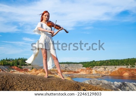 beautiful woman in elegant white dress and floral wreath playing violin on seashore Stock photo © 
