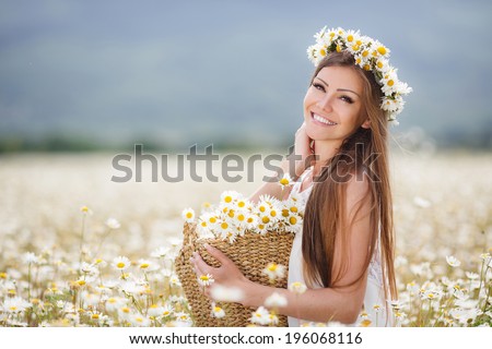 Beautiful woman enjoying daisy field, nice female lying down in meadow of flowers, pretty girl relaxing outdoor, having fun, holding plant, happy young lady and spring green nature, harmony concept