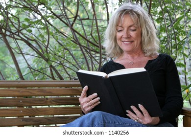 A Beautiful Woman Enjoying A Good Book On Her Porch Swing.