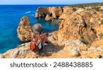 Beautiful woman enjoying panoramic view of rocky beaches with cliffs, Algarve in Porugal