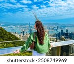 The beautiful woman enjoys the amazing view from above of Hong Kong City from Victoria Peak