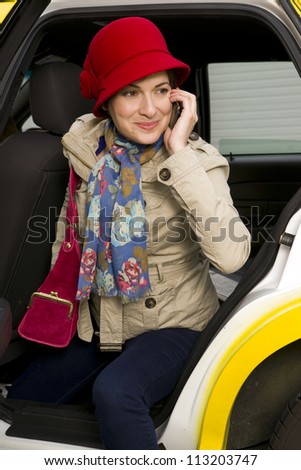 Beautiful woman exits a yellow taxi while talking on her cell phone