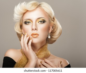 Beautiful woman face with luxury gold makeup