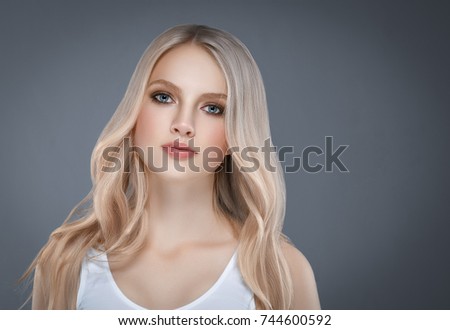 Beautiful Woman Face Portrait Beauty Skin Care Concept with long blonde hair. Fashion Beauty Model with beautiful hairstyle over gray background
