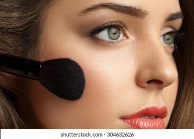 Beautiful woman face powders, and apply blush to the cheekbones