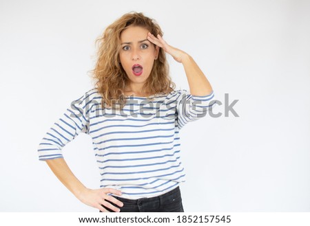 Beautiful woman with facial expression of surprise wearing casual striped t-shirt standing over white background.