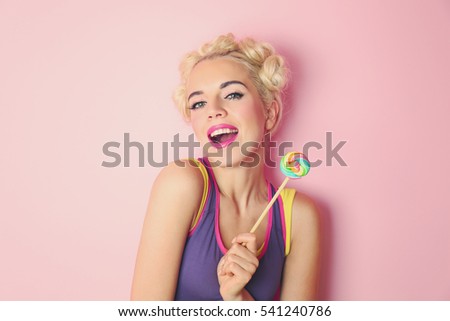 Beautiful woman with fashion hairstyle and lollipop on pink background