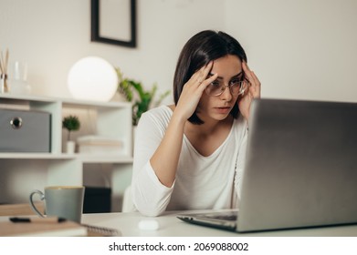 Beautiful woman feeling tired and stressed while using a laptop and working remotely from home