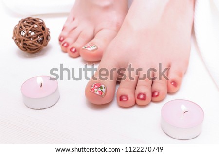 Beautiful woman feet and burning candles on white wooden background. Legs care concept.