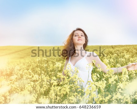 Beautiful woman in field with yellow flowers at summer sunset