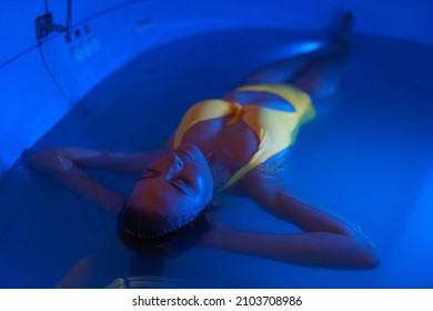 Beautiful Woman Floating In Tank Filled With Dense Salt Water Used In Medical Therapy.