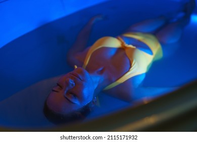 Beautiful Woman Floating In Tank Filled With Dense Salt Water Used In Medical Therapy.