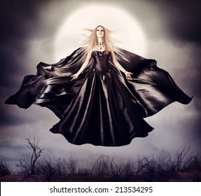 Beautiful woman - flying halloween witch in midnight outdoor about full moon with black developing cloak