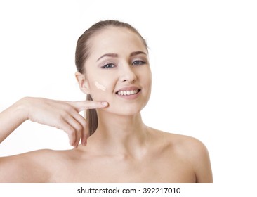 Beautiful woman with a foundation cream on her face, isolated on white background