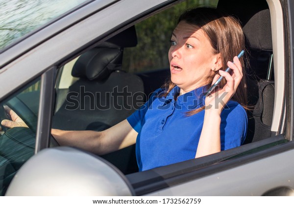 Beautiful woman, frightened fearful girl, driver,\
young shocked lady about to have traffic accident, driving car,\
holding in hand, talking on cell mobile phone on road. Unfastened\
by a seat belt