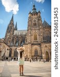 A beautiful woman in front of St. Vitus Cathedral at Prague Castle in Prague under Clear Blue Sky Sunny Summer. Full of Tourist people