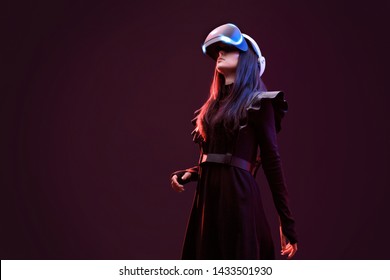 Beautiful woman in futuristic dress over dark background. Girl in glasses of virtual reality. Augmented reality, science, future technology, robots and people concept. VR.