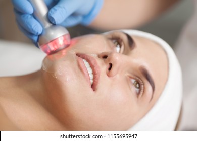 Beautiful Woman Getting Radio Frequency Lifting On Her Face. Professional Beautician Doing Anti-wrinkle Facial Treatment. Concept Of Skin Care And Correction Of Skin Texture.