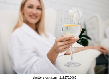 Beautiful woman with glass of refreshing lime drink during intravenous detox therapy with IV drip Infusion. Detox treatments at spa