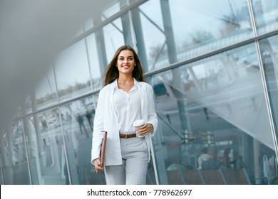 Beautiful Woman Going To Work With Coffee Walking Near Office Building. Portrait Of Successful Business Woman Holding Cup Of Hot Drink In Hand On Her Way To Work On City Street. High Resolution.