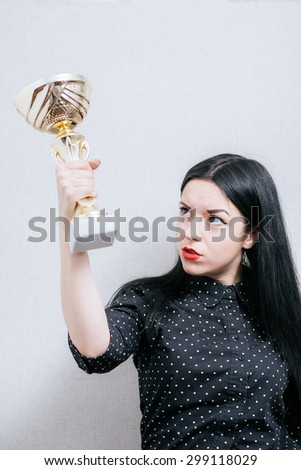 Beautiful woman with a gold cup. On a gray background.