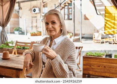 A beautiful woman with gray hair relaxes while sipping coffee in a cozy cafe setting - Powered by Shutterstock