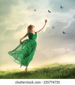 Beautiful woman in a green dress chasing butterflies on a mountain