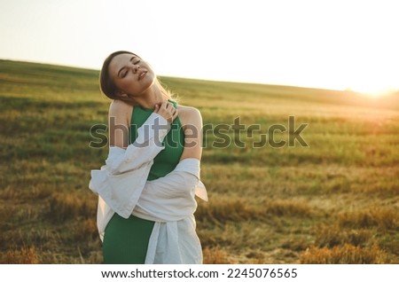 Beautiful woman in a green dress. Photo of a girl in a field at sunset. Atmospheric photo in a field in sunlight.Blonde with short hair.sensual photo of a girl.delicate portrait.sunset portrait.