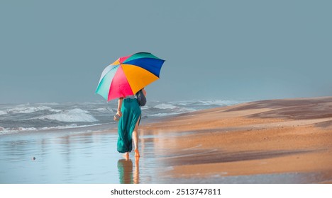 Beautiful woman in a green skirt with a colorful umbrella walks barefoot on the beach - The Namib desert along side the Atlantic ocean coast of Namibia with crescent moon - Namiba, Southern Africa - Powered by Shutterstock