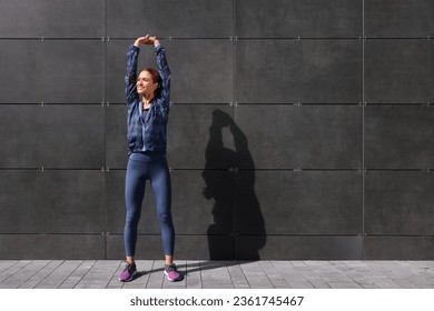 Beautiful woman in gym clothes doing exercises on street, space for text - Powered by Shutterstock