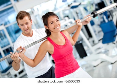 Beautiful Woman At The Gym Exercising With Her Trainer