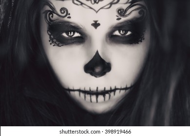 Beautiful woman with halloween sugar skull make-up at winter.
Makeup girl like sugar skull - a symbol of Day of the Dead holiday.
Symbolism to celebrate Day of the Dead. Black and white photo.