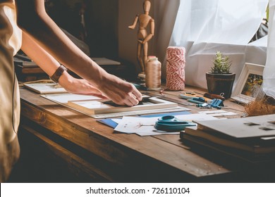 Beautiful Woman Hand Crafting Book At The Tabletop With Stationery. Stylish Craftswoman With Stationery Work At His Hipster Workstation.