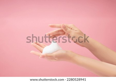 A beautiful woman hands with white foam mousse placed on over a pink background. Cosmetic product promotion