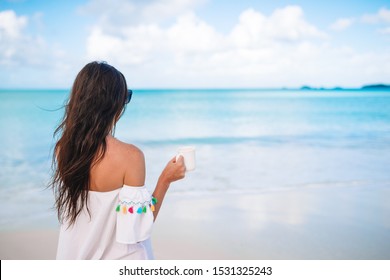 Beautiful woman has breakfast on the beach enjoying sweet coffee