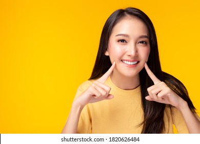 Beautiful woman has beautiful tooth, white teeth, nice tooth alignment. Pretty girl show her teeth. Asian female get beauty braces. Attractive lady get confidence copy space, yellow background